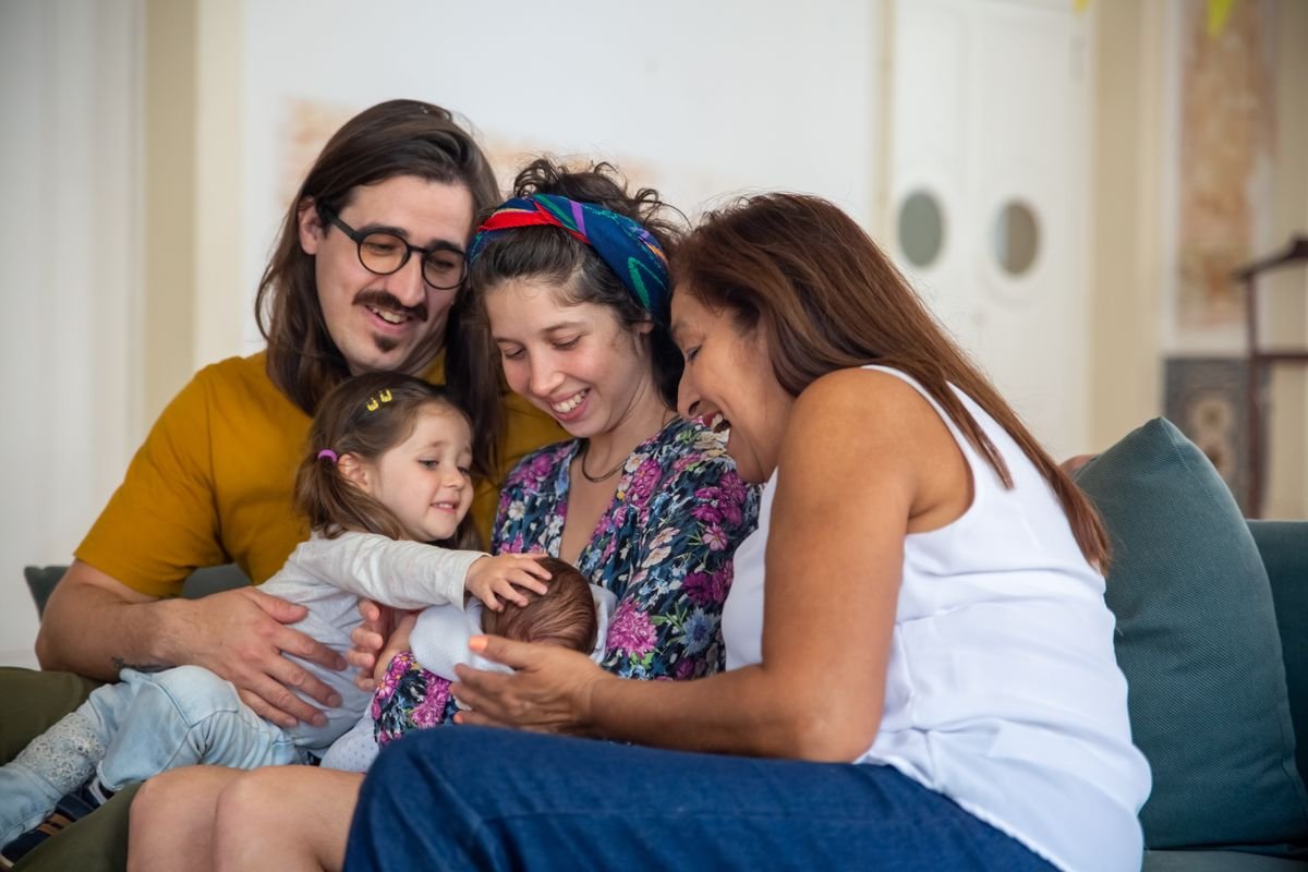 Famille de trois générations réunie à la maison, illustrant la transmission de patrimoine entre générations