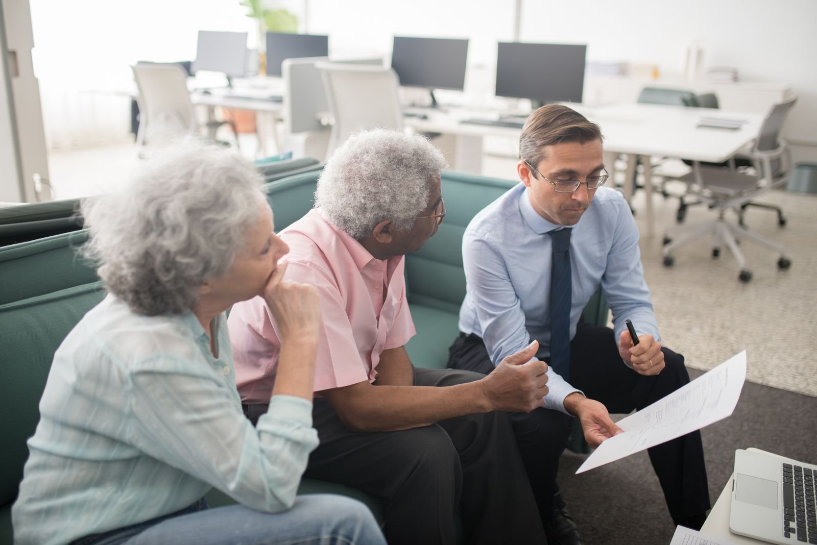 Un conseiller en gestion de patrimoine présente des documents à un couple de clients lors d'un rendez-vous