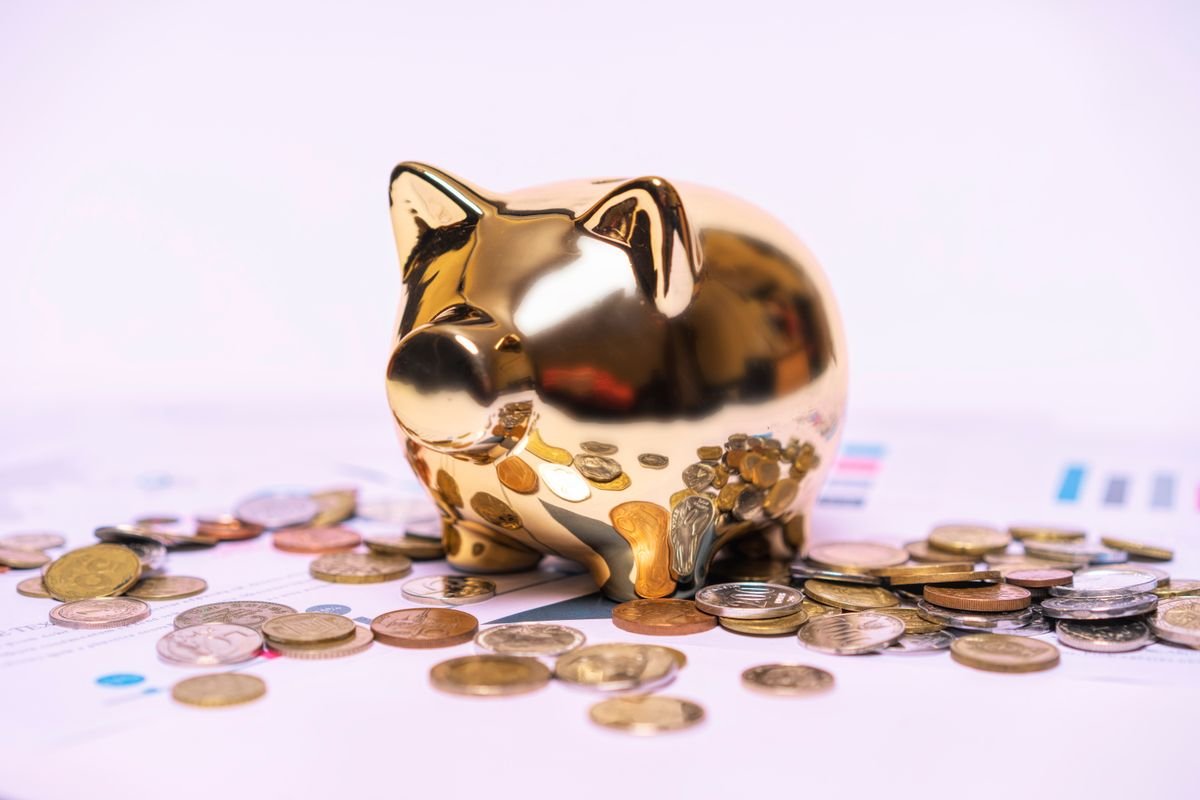Une tirelire dorée posée sur des documents financiers avec des pièces de monnaie, symbole de l'épargne retraite