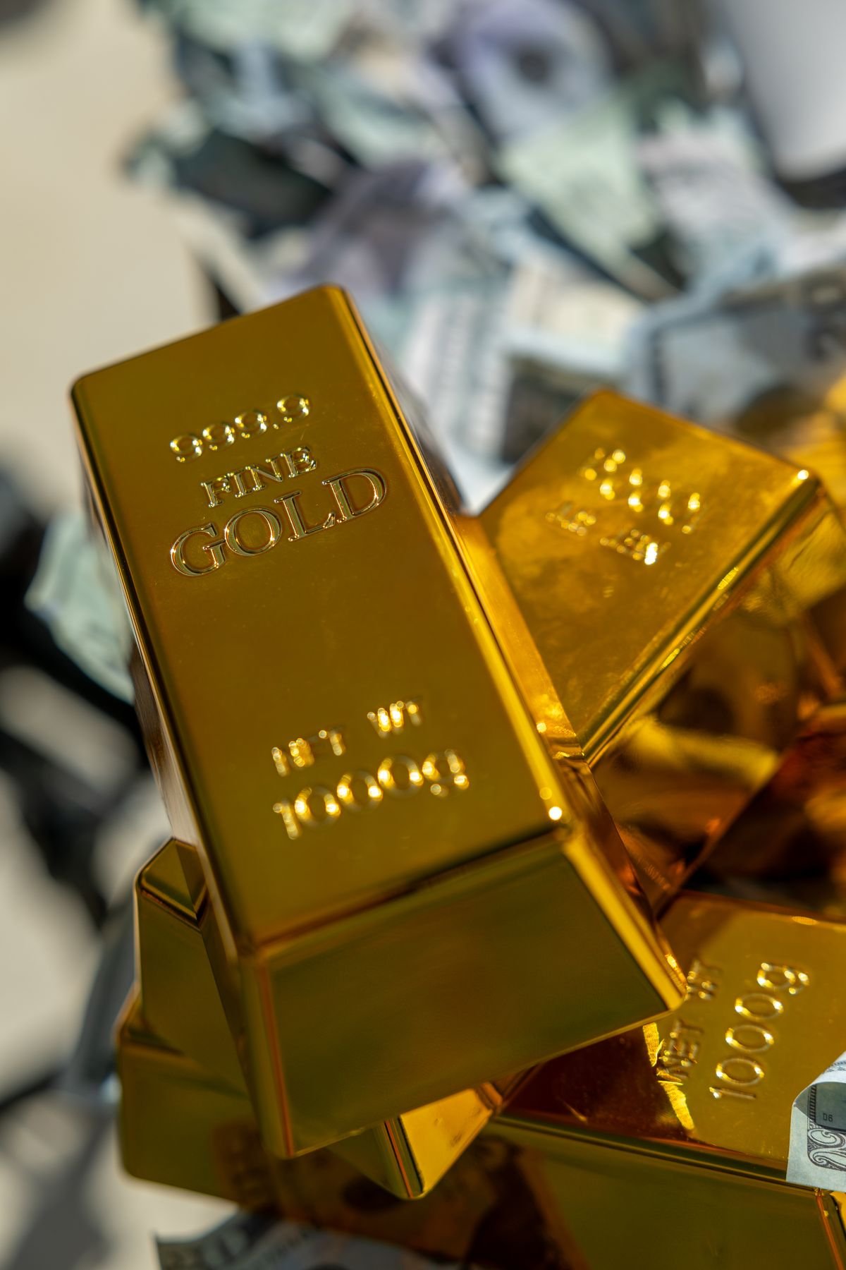 Empilement de lingots d'or posés sur des billets, l'or comme valeur refuge